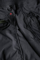 Close-up of black pants with a brand logo on a white background