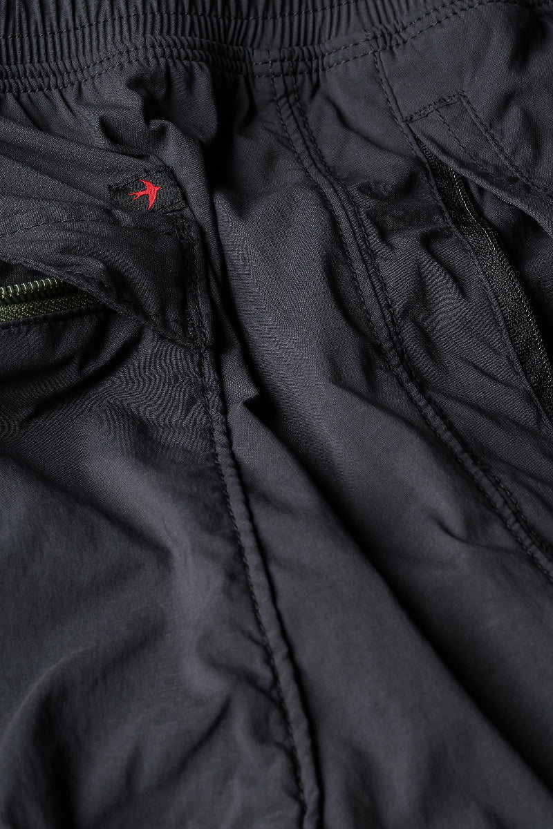 Close-up of black pants with a brand logo on a white background