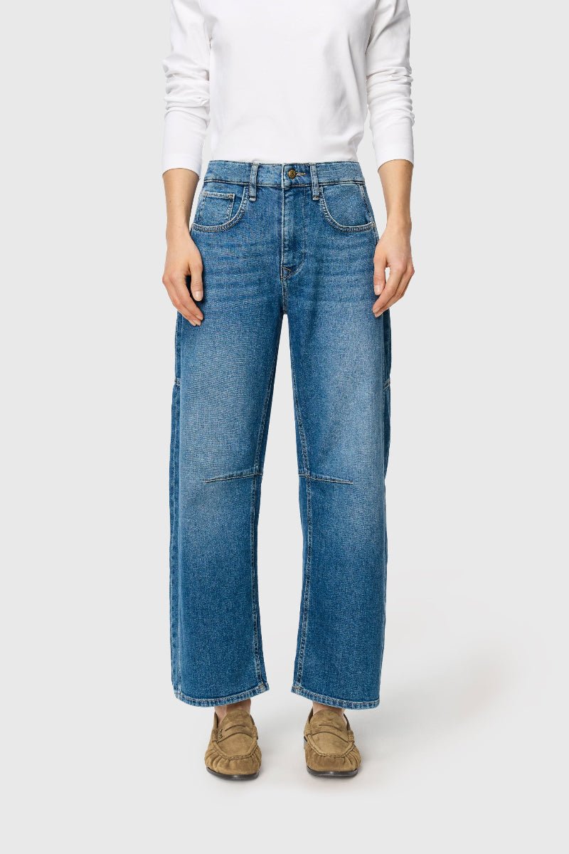 Person wearing blue jeans and a white sweater on a white background