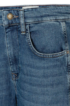 Close-up of blue denim jeans with a button and back pocket on a white background