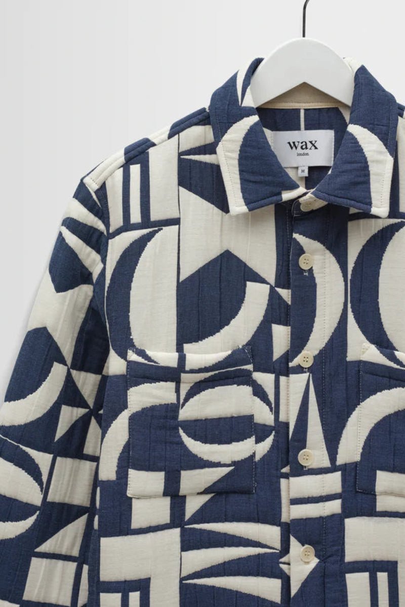 Blue and white patterned coat on a hanger against a white background