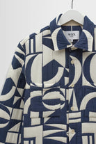 Blue and white patterned coat on a hanger against a white background