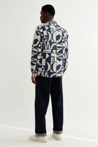 Person wearing a patterned sweater and dark pants on a white background