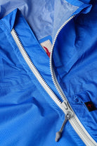 Close-up of a blue jacket with a zipper, showing brand logos.