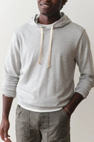 Person wearing a gray hoodie and gray pants against a plain background