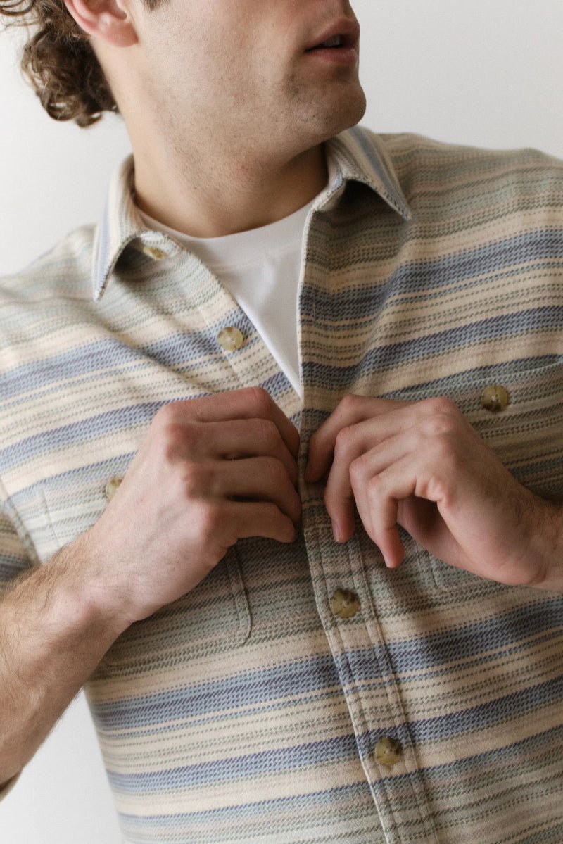Man wearing a striped shirt with a neutral background
