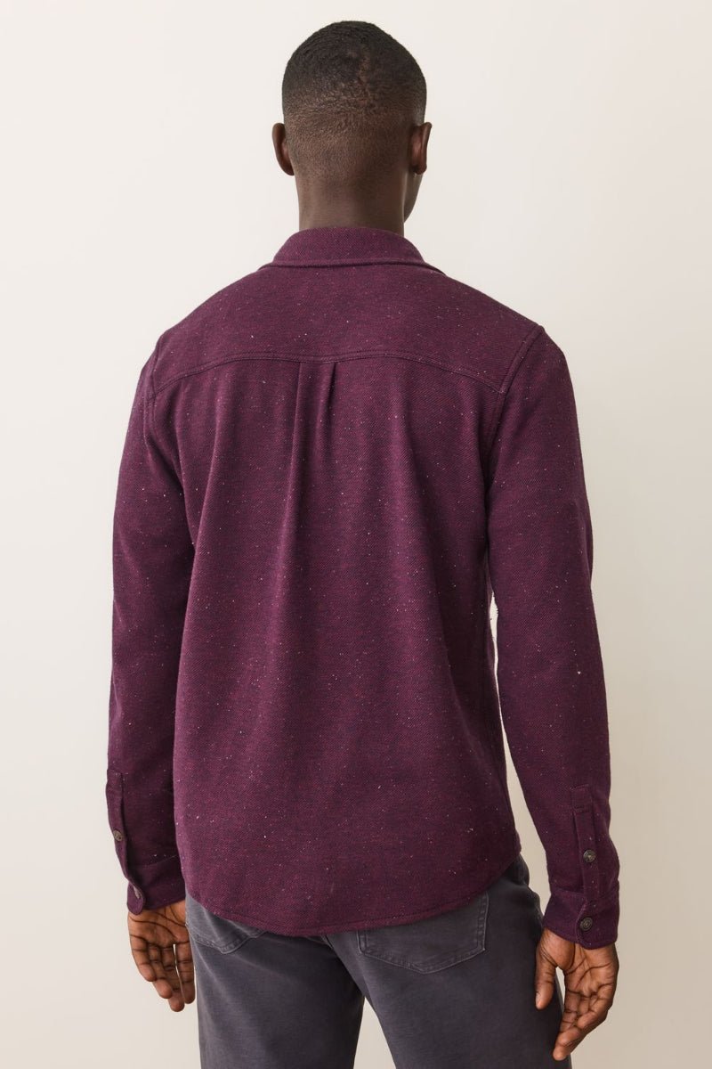 Person wearing a maroon shirt from behind on a plain background