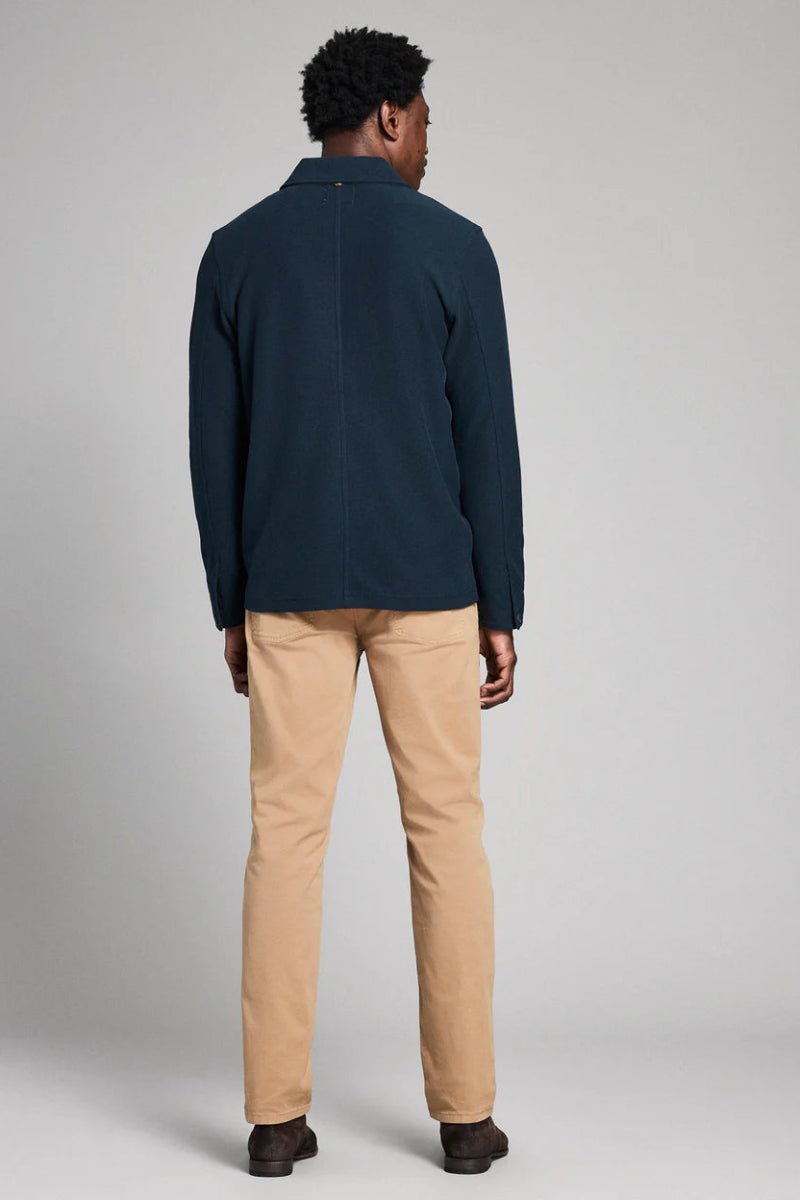 Person wearing a navy jacket and beige pants on a plain background