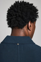 Person wearing a navy blue polo shirt against a gray background