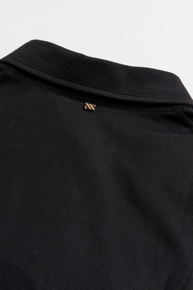 Close-up of a black garment with a brand logo on a white background