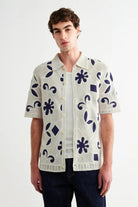 Man wearing a patterned short-sleeve shirt on a white background