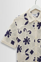 Short-sleeve shirt with floral pattern on a hanger against a white background