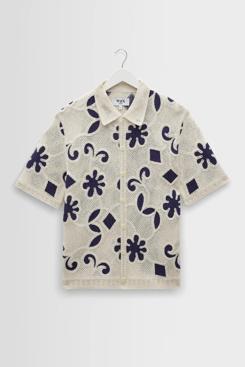 Short-sleeve shirt with floral pattern on a hanger against a white background