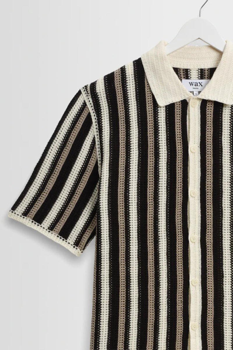 Black and white striped shirt on a hanger against a light gray background