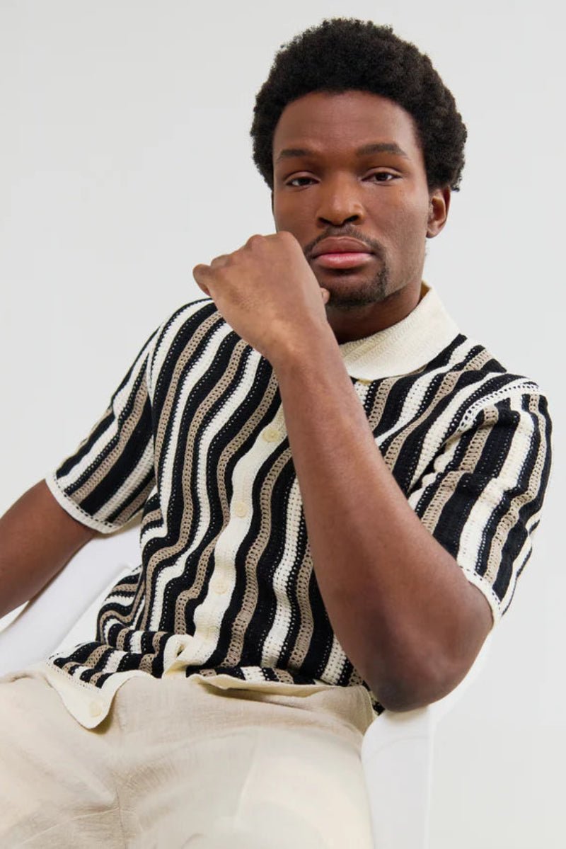 Man wearing a black and white striped sweater against a plain background