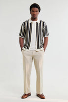 Man wearing a black and white striped shirt with beige pants on a white background