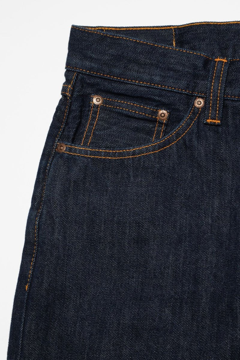Close-up of dark blue denim jeans with stitching details on a white background
