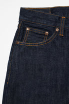 Close-up of dark blue denim jeans with stitching details on a white background