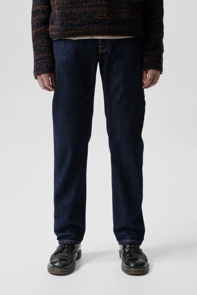 Person wearing dark blue jeans and a patterned sweater on a white background