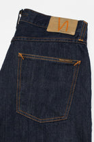 Dark blue denim jeans with a brand label on a light gray background
