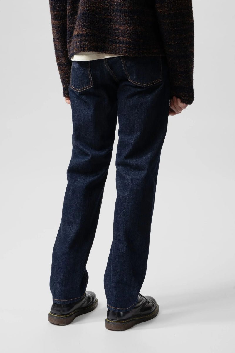 Person wearing dark blue jeans and a patterned sweater on a white background