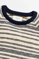 Close-up of a striped sweater with a visible brand label on a white background