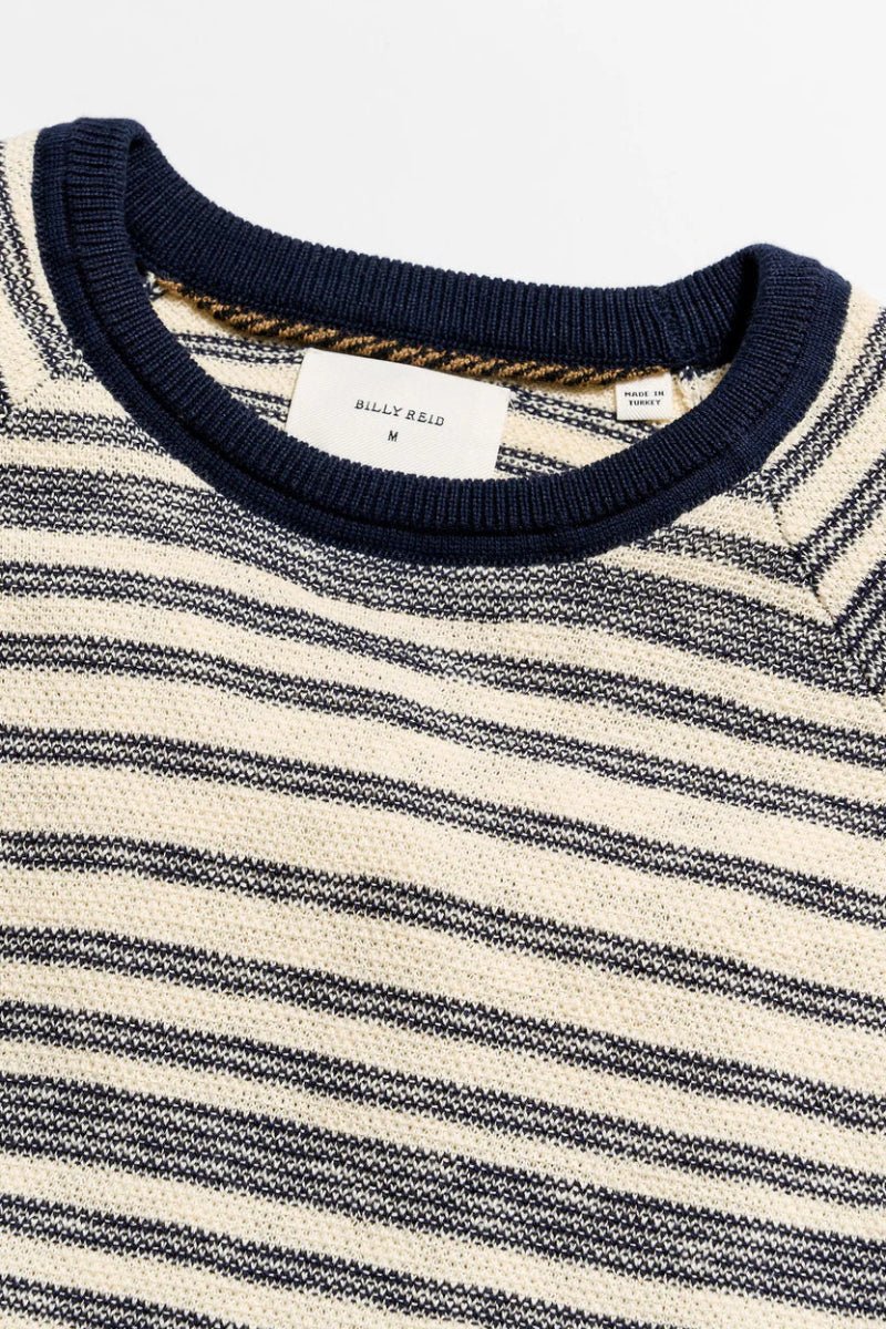 Close-up of a striped sweater with a visible brand label on a white background