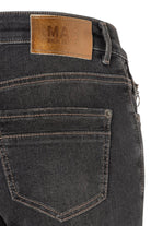 Close-up of dark denim jeans with a visible brand label on a white background