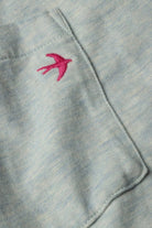 Close-up of a light gray fabric with a pink embroidered bird design.
