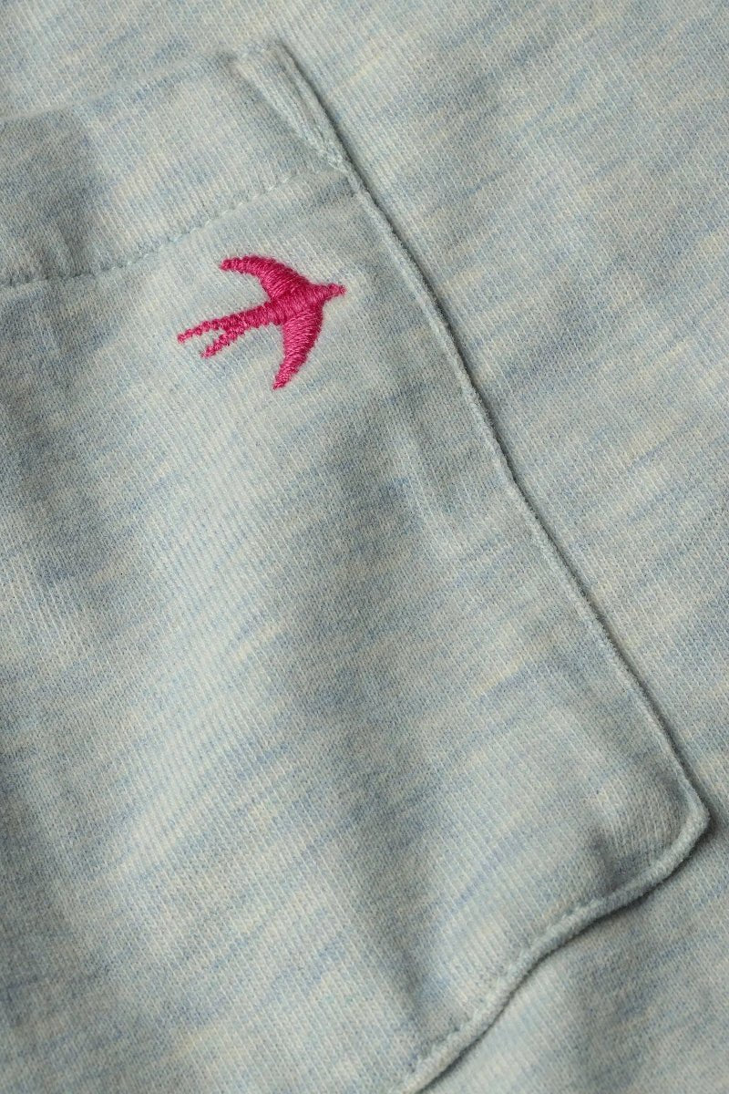 Close-up of a light gray fabric with a pink embroidered bird design.