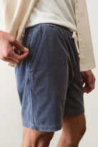 Person wearing blue shorts and a beige jacket on a plain background