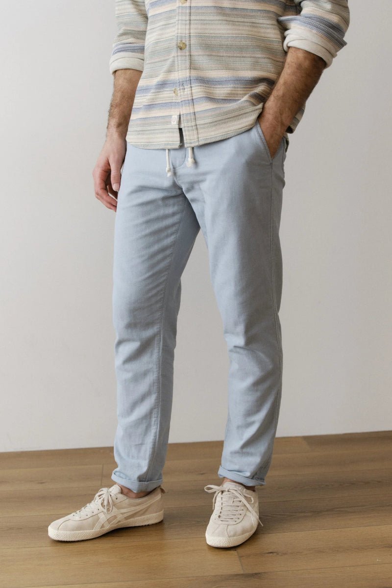 Person wearing light blue pants and a striped shirt on a plain background