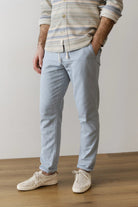 Person wearing light blue pants and a striped shirt on a plain background