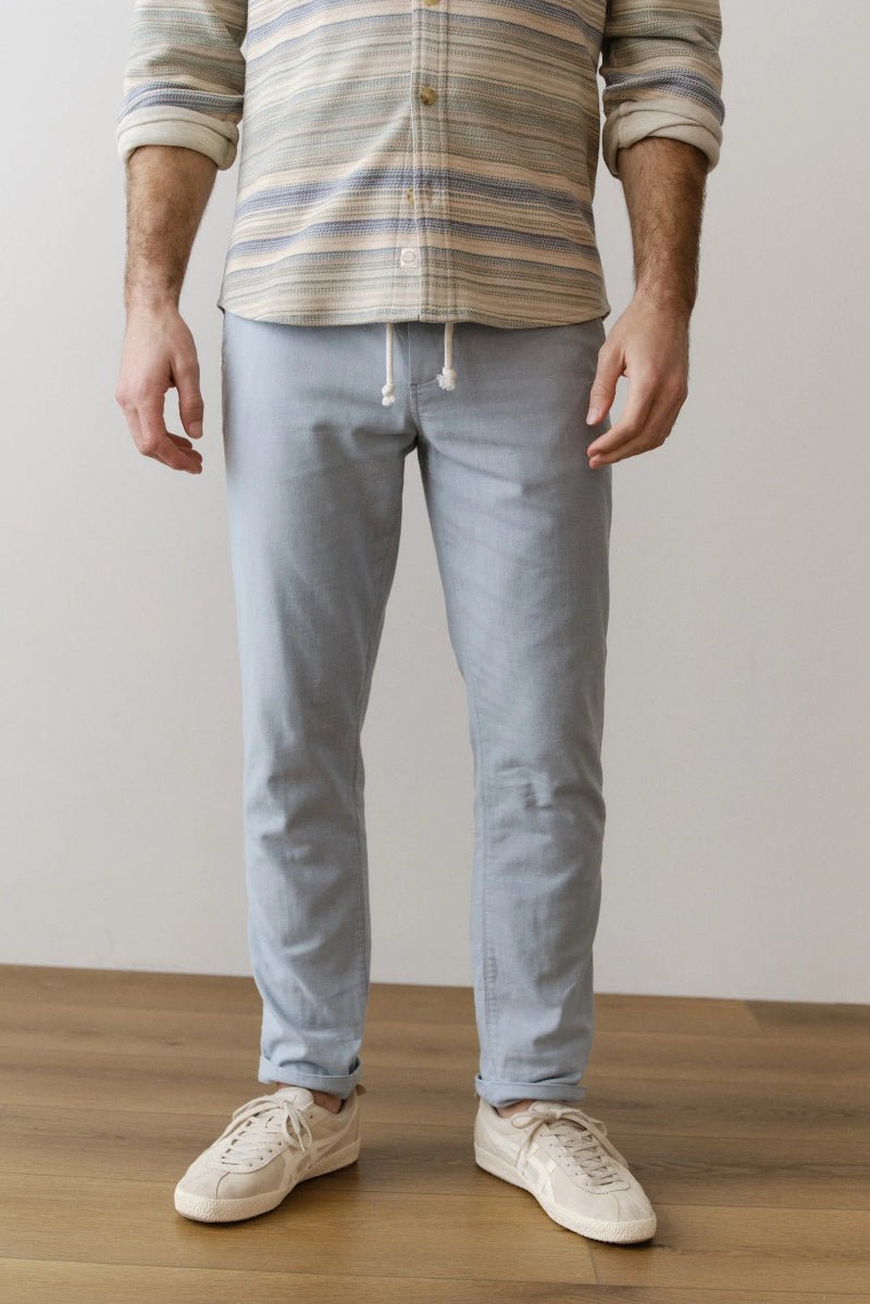 Person wearing a striped shirt and light blue pants on a wooden floor.