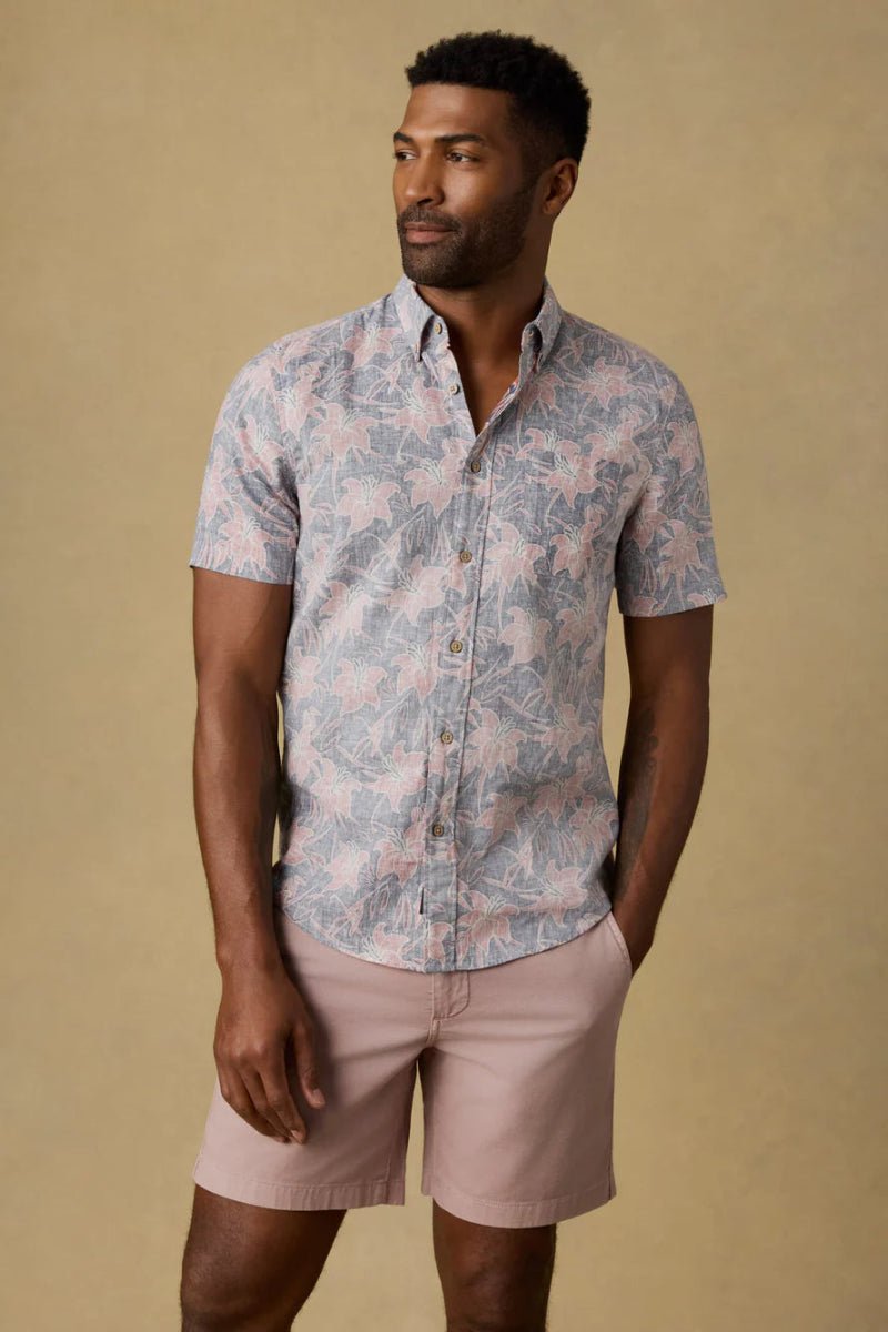 Man wearing a patterned shirt and pink shorts against a beige background