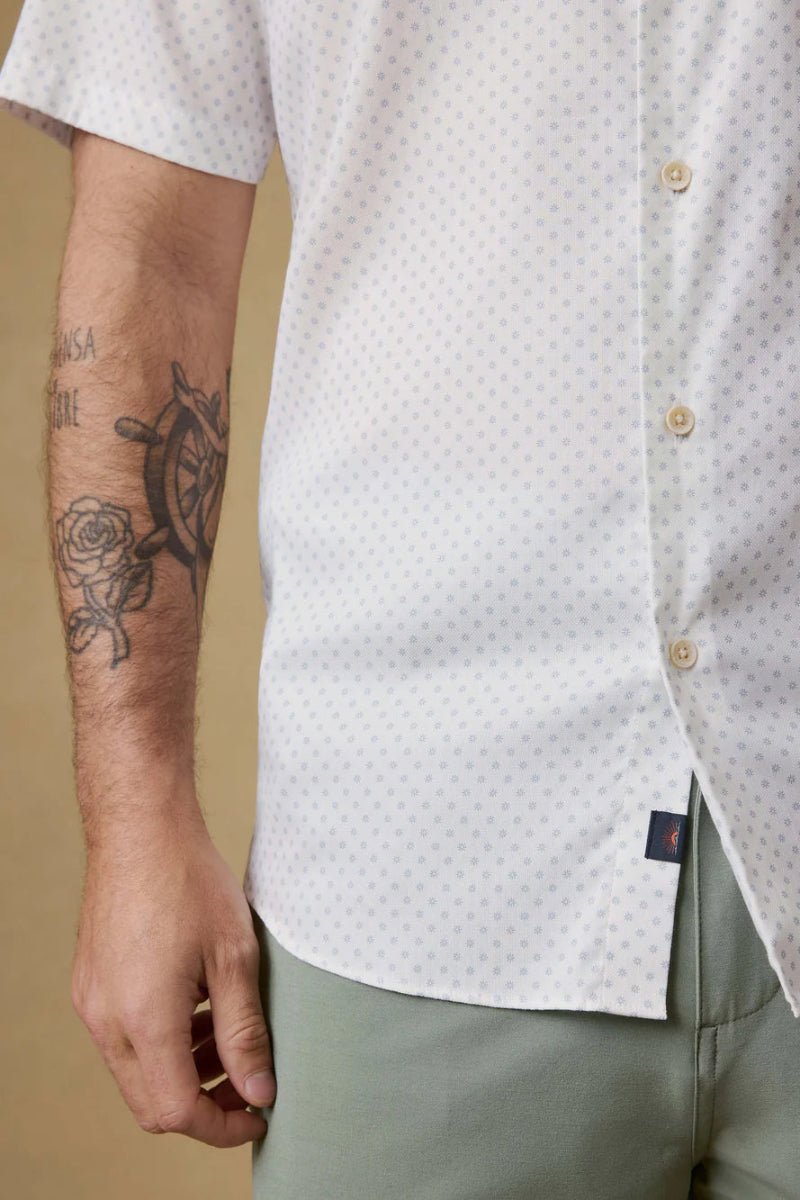 Close-up of a person wearing a patterned shirt with a visible brand label.