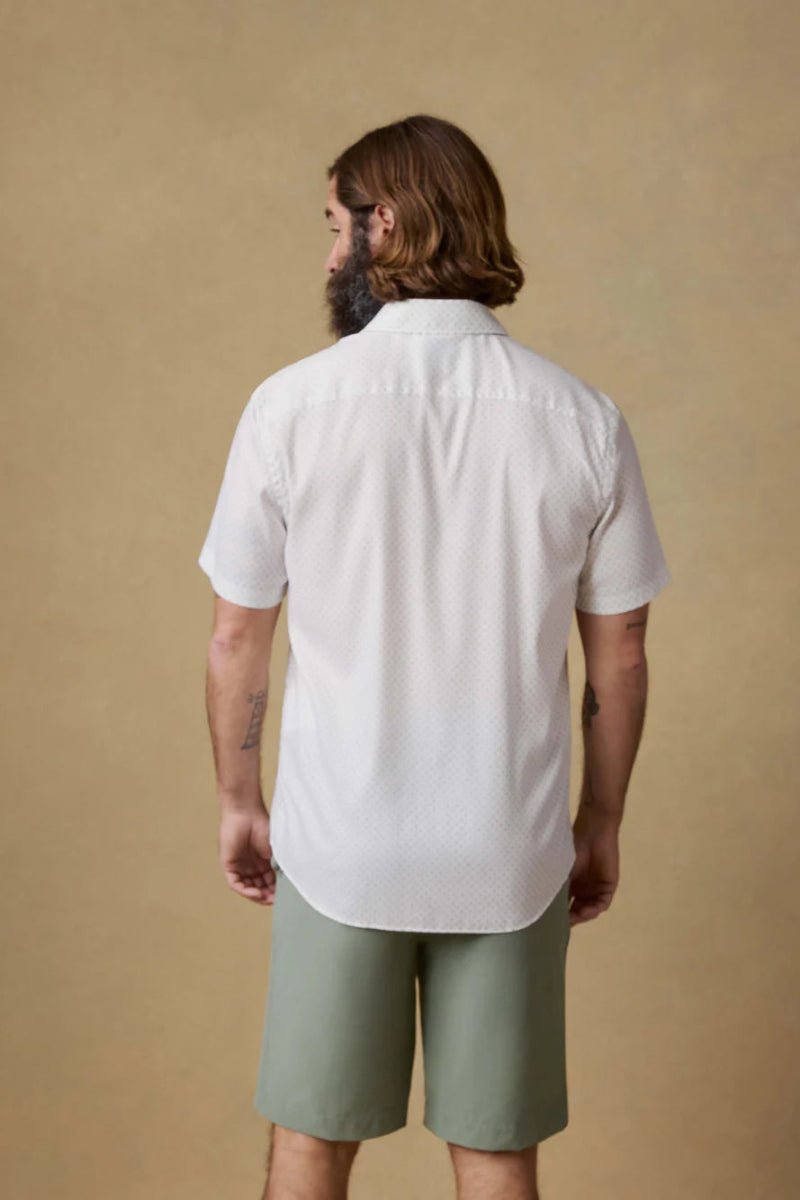 Man wearing a white shirt and green shorts against a beige background