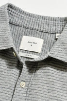 Close-up of a gray textured shirt with a brand label on a light gray background