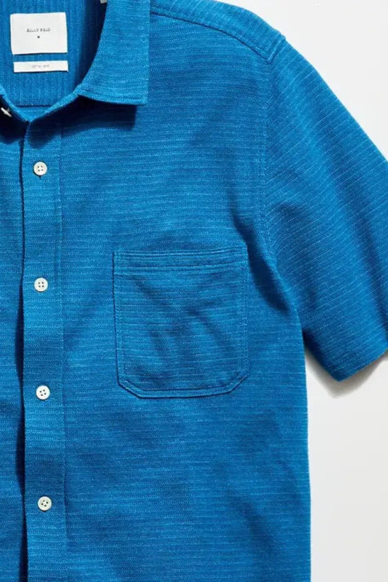 Blue short-sleeve shirt with buttons on a light gray background