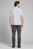 Man wearing a light gray polo shirt and dark gray pants on a plain background