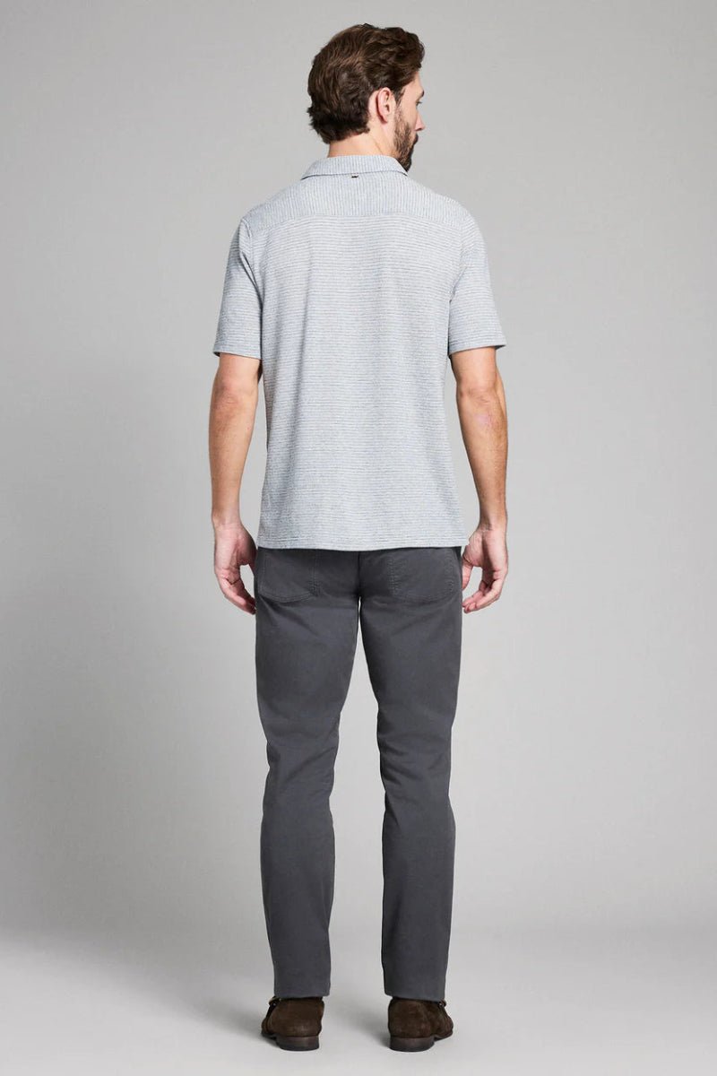 Man wearing a light gray polo shirt and dark gray pants on a plain background