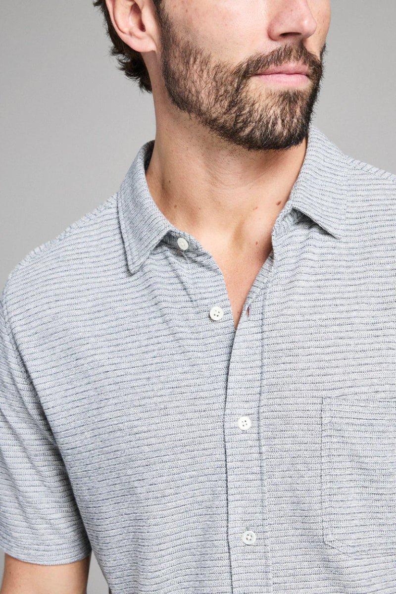 Man wearing a gray striped shirt against a gray background