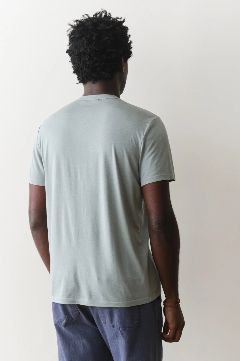 Person wearing a light green t-shirt and blue pants against a white background