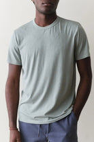 Person wearing a light gray t-shirt and blue pants against a plain background