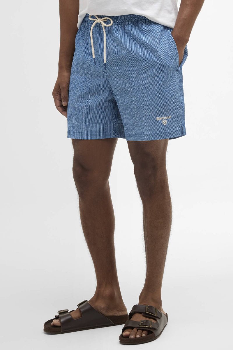 Person wearing blue patterned shorts on a white background