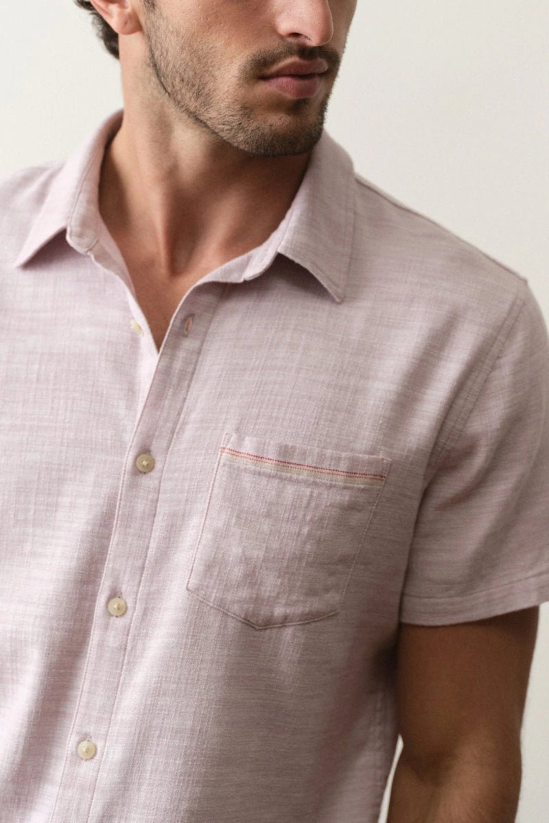 Man wearing a light pink short-sleeve shirt with a neutral background