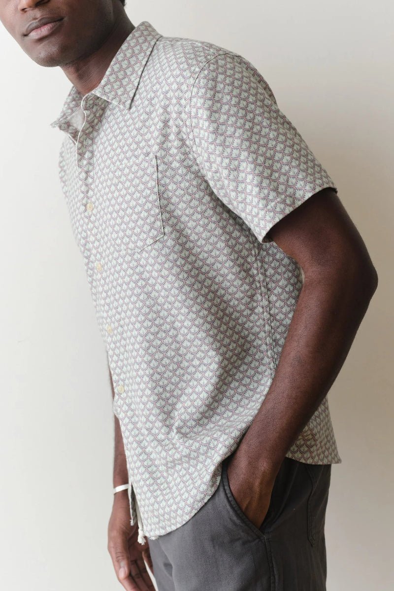 Man wearing a patterned short-sleeve shirt against a plain background