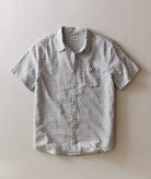 Short-sleeve button-up shirt with geometric pattern on a beige background