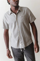 Man wearing a patterned short-sleeve shirt against a plain background