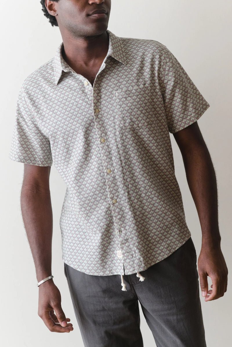 Man wearing a patterned short-sleeve shirt against a plain background